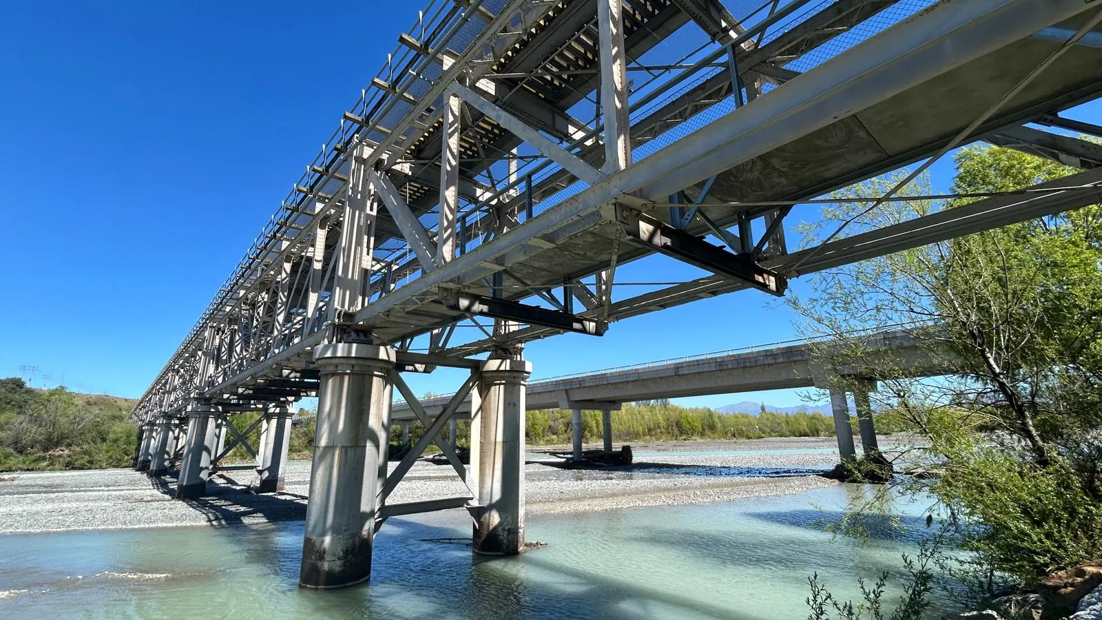 Steel and concrete bridge structure over river showing civil infrastructure asset requiring inspection and remediation.